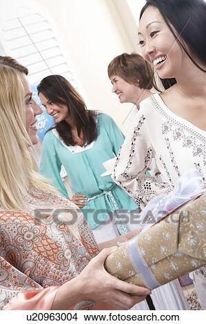 Woman giving a gift at baby shower View Large Photo Image Picture - Woman giving a gift at baby shower. Fotosearch
