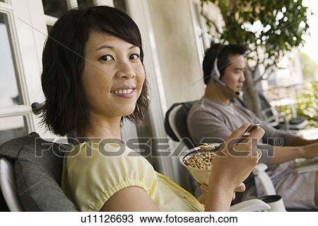 Woman having breakfast on porch, man using laptop in background View Large Photo Image Stock Image - Woman having breakfast on porch, man using laptop in background. Fotosearch