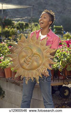 Stock Photograph - Woman holding garden art at plant nursery. Fotosearch
