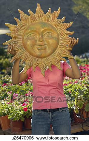Woman holding model sun over face at plant nursery View Large Photo Image Stock Photograph - Woman holding model sun over face at plant nursery. Fotosearch