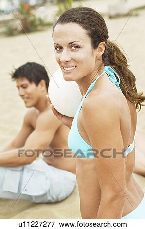 Stock Photo - Woman in Bikini smiling, holding volleyball on Beach, portrait. Fotosearch