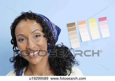 Stock Photo - Woman in front of paint colour samples on interior wall, close-up, portrait. Fotosearch