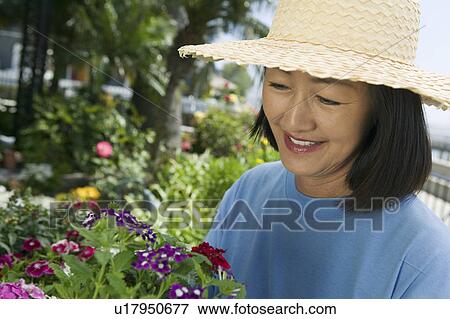 Stock Photo - Woman in straw hat gardening. Fotosearch