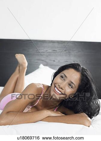 Stock Photograph - Woman in underwear reclining on bed. Fotosearch
