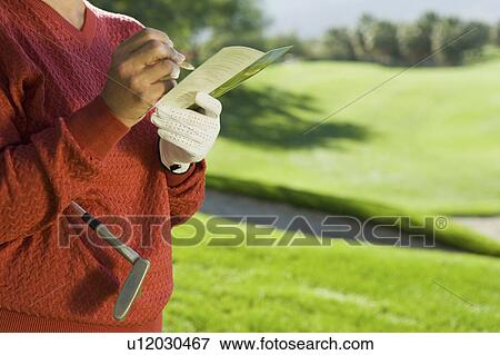 Stock Photo - Woman marking score on score card, close-up of hands, (mid section). Fotosearch