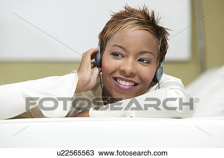 Woman on couch Listening to Headphones, front view, close up View Large Photo Image Stock Image - Woman on couch Listening to Headphones, front view, close up. Fotosearch