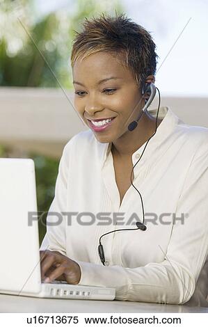 Woman on patio using laptop and headset View Large Photo Image Stock Photography - Woman on patio using laptop and headset. Fotosearch