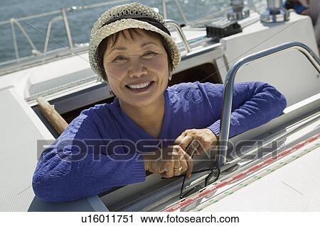 Stock Image - Woman on sailboat, smiling, (portrait). Fotosearch