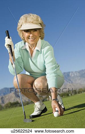 Woman picking golf ball, (portrait) View Large Photo Image Picture - Woman picking golf ball, (portrait). Fotosearch