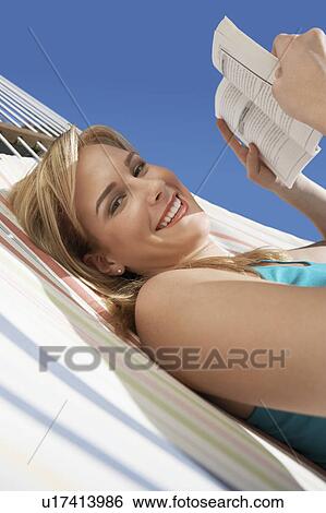 Stock Photograph - Woman reading in hammock, half length. Fotosearch