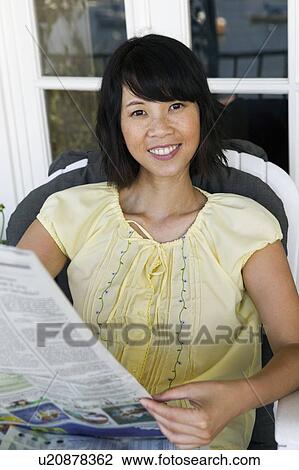 Stock Image - Woman relaxing on armchair outdoors, (portrait). Fotosearch