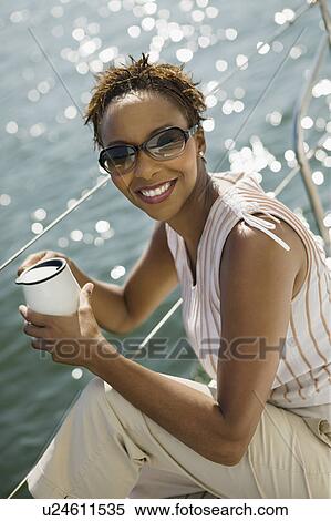 Stock Photography - Woman relaxing on yacht, (portrait), (elevated view). Fotosearch