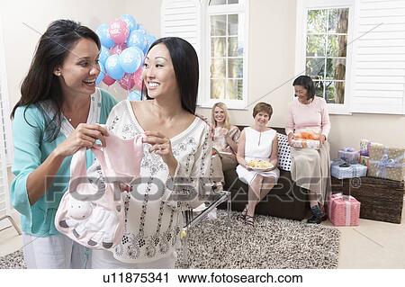 Stock Image - Woman showing gift at baby shower. Fotosearch