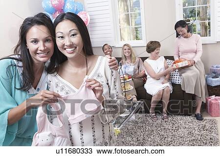 Stock Image - Woman showing off gift at baby shower. Fotosearch