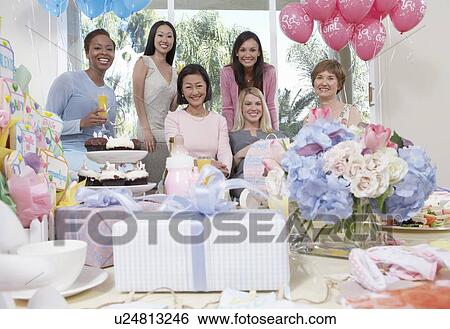 Stock Photograph - Woman sitting at baby shower behind table of gifts. Fotosearch