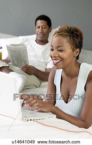 Stock Photo - Woman sitting in living room Using Laptop. Fotosearch