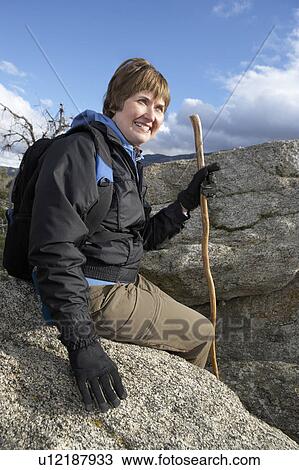 Stock Image - Woman sitting on rock in mountains. Fotosearch