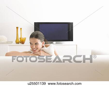 Stock Photo - Woman sitting on sofa in modern living room. Fotosearch