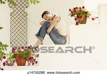Stock Photograph - Woman Sitting on staircase in garden, side view portrait.. Fotosearch