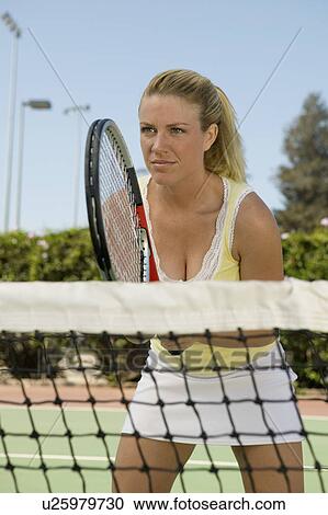 Stock Image - Woman standing at Tennis Net waiting for serve. Fotosearch