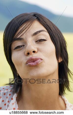 Stock Photo - Woman standing in mountain field Blowing Kiss, portrait, close up. Fotosearch