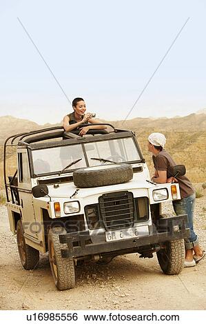 Woman taking photograph of man standing by four wheel drive car View Large Photo Image Stock Photograph - Woman taking photograph of man standing by four wheel drive car. Fotosearch