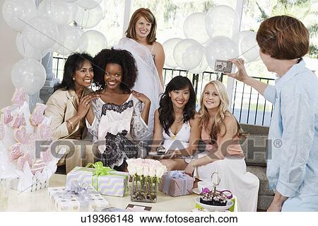 Stock Photo - Woman Taking Pictures of friends sitting on sofa at Party. Fotosearch