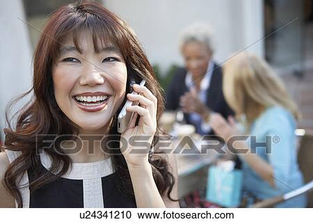 Stock Image - Woman Talking on Cell Phone, friends drinking coffee drinks. Fotosearch