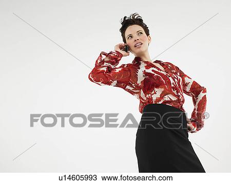 Stock Image - Woman using cell phone in studio. Fotosearch