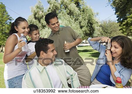 Woman using digital camera, photographing son (13-15) with father, brother, and sister. View Large Photo Image Stock Image - Woman using digital camera, photographing son (13-15) with father, brother, and sister.. Fotosearch