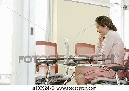 Stock Photo - Woman using laptop in conference room. Fotosearch