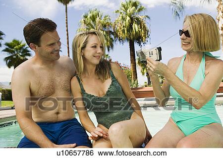Woman video taping couple by pool. View Large Photo Image Stock Photograph - Woman video taping couple by pool.. Fotosearch