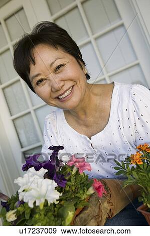 Stock Photo - Woman with flowers, outdoors, (portrait). Fotosearch
