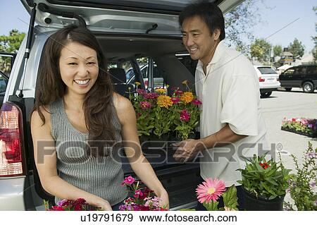 Stock Photo - Woman with husband Loading flowers into back of SUV, portrait. Fotosearch