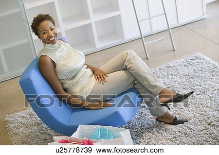Stock Photo - Woman With Shopping Bags Relaxing on Chair, portrait. Fotosearch