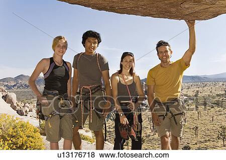 Stock Photo - Young Climbers standing Underneath Rock, (portrait). Fotosearch