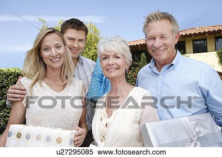 Young couple and older couple standing outside holding presents View Large Photo Image Stock Photography - Young couple and older couple standing outside holding presents. Fotosearch