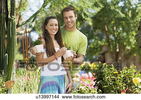 Young couple choosing potted flowers in garden centre, (portrait) View Large Photo Image Picture - Young couple choosing potted flowers in garden centre, (portrait). Fotosearch