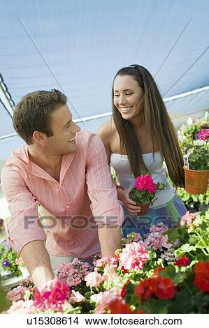 Picture - Young couple choosing potted flowers in garden centre. Fotosearch