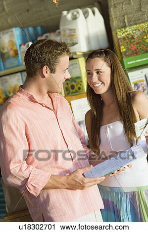 Stock Image - Young couple in garden centre. Fotosearch