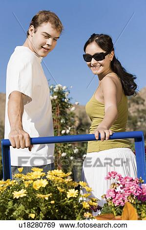 Stock Photo - Young couple looking at potted flowers in garden centre. Fotosearch