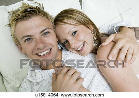 Picture - Young couple lying on sofa, portrait, close up. Fotosearch