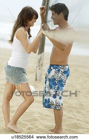 Young couple on Beach standing with Volleyball Net between Them, side view View Large Photo Image Picture - Young couple on Beach standing with Volleyball Net between Them, side view. Fotosearch