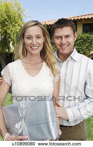 Young Couple Posing outside, holding present View Large Photo Image Stock Image - Young Couple Posing outside, holding present. Fotosearch