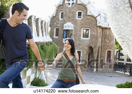 Stock Image - Young couple sightseeing, holding hands. Fotosearch