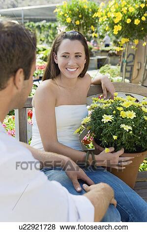 Stock Photo - Young couple sitting on bench in garden centre. Fotosearch