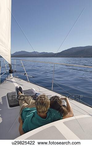 Young couple sitting on sailboat, rear view, (elevated view) View Large Photo Image Stock Image - Young couple sitting on sailboat, rear view, (elevated view). Fotosearch