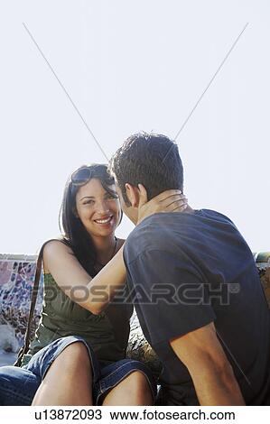 Young couple sitting on stone bench, portrait View Large Photo Image Stock Image - Young couple sitting on stone bench, portrait. Fotosearch