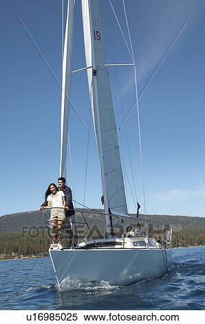 Stock Photography - Young couple standing on bow of sailboat. Fotosearch