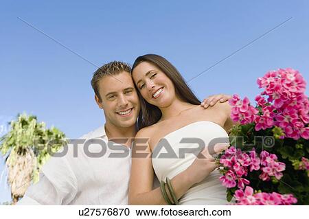 Young couple with potted flower against clear sky, (portrait), (low angle view) View Large Photo Image Stock Image - Young couple with potted flower against clear sky, (portrait), (low angle view). Fotosearch